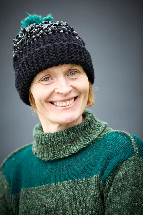 Portræt af Lotte Kjær i grøn striksweater og sort hue med pompon